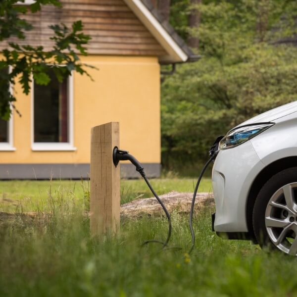 Houten oplaadpaal in het gras met elektrische auto